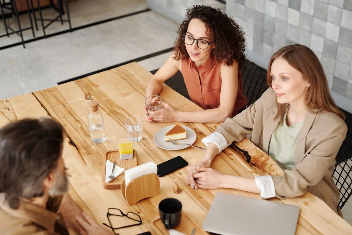 People in conversation around a table in a bright café